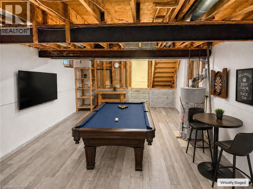 Lower-level recreation space featuring wood-finish flooring and exposed ceiling joists - 102 Juniper Drive, Hamilton, ON