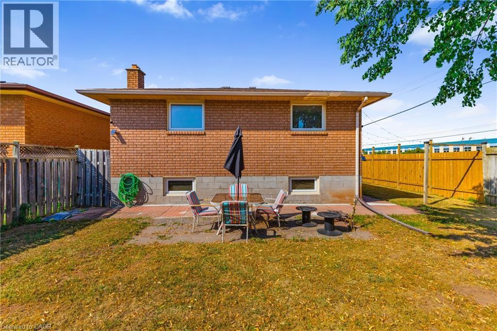 Expansive backyard featuring a brick exterior, a concrete patio, and a wood privacy fence - 102 Juniper Drive, Hamilton, ON