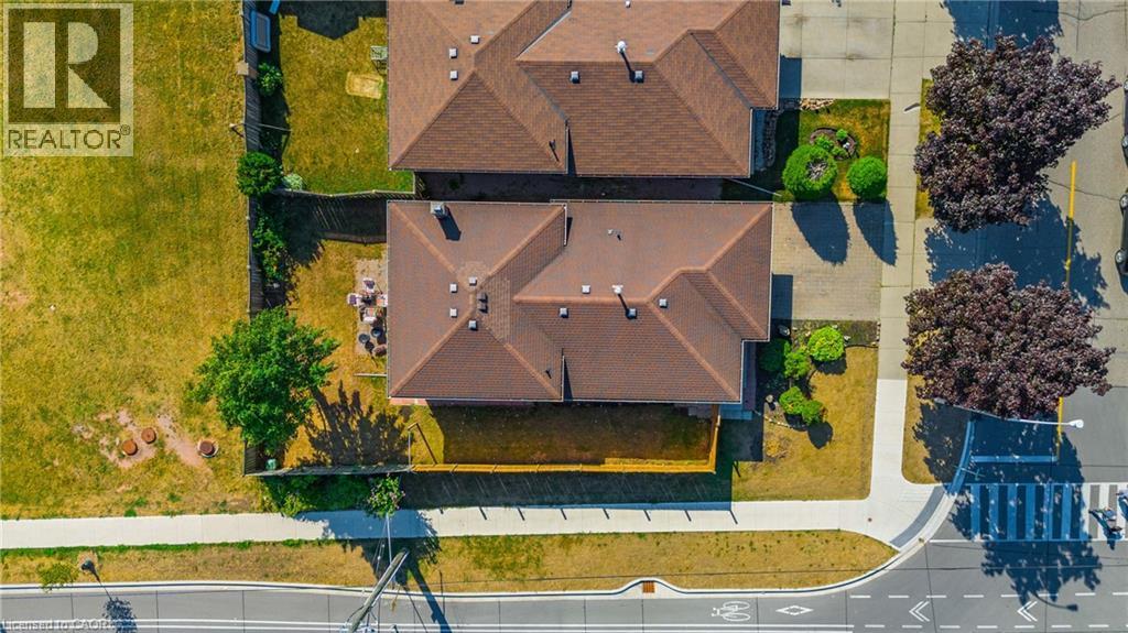 Property featuring a brown shingled roof and a private fenced yard with a paved patio area - 102 Juniper Drive, Hamilton, ON