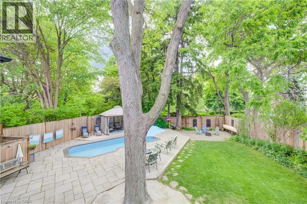 Expansive backyard with a swimming pool, surrounding patio pavers, and a fire pit area - 314 Glasgow Street, Kitchener, ON