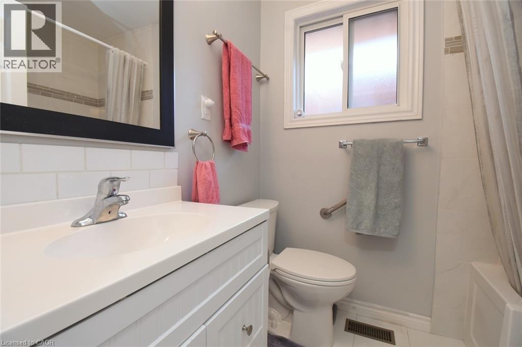 Bathroom featuring a white vanity with integrated sink, chrome faucet, and subway tile backsplash - 185 Rosslyn Avenue N, Hamilton, ON - Indoor Photo Showing Bathroom