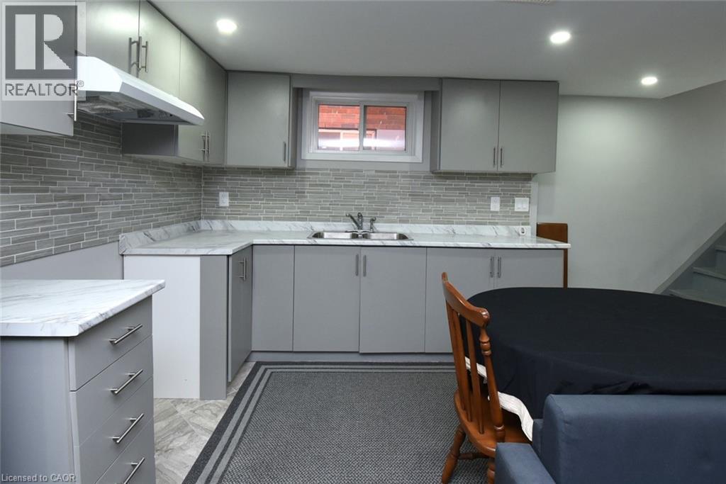 Contemporary kitchen featuring gray cabinetry with brushed nickel hardware, white stone-look countertops, and a gray subway tile backsplash - 185 Rosslyn Avenue N, Hamilton, ON - Indoor Photo Showing Kitchen With Double Sink With Upgraded Kitchen