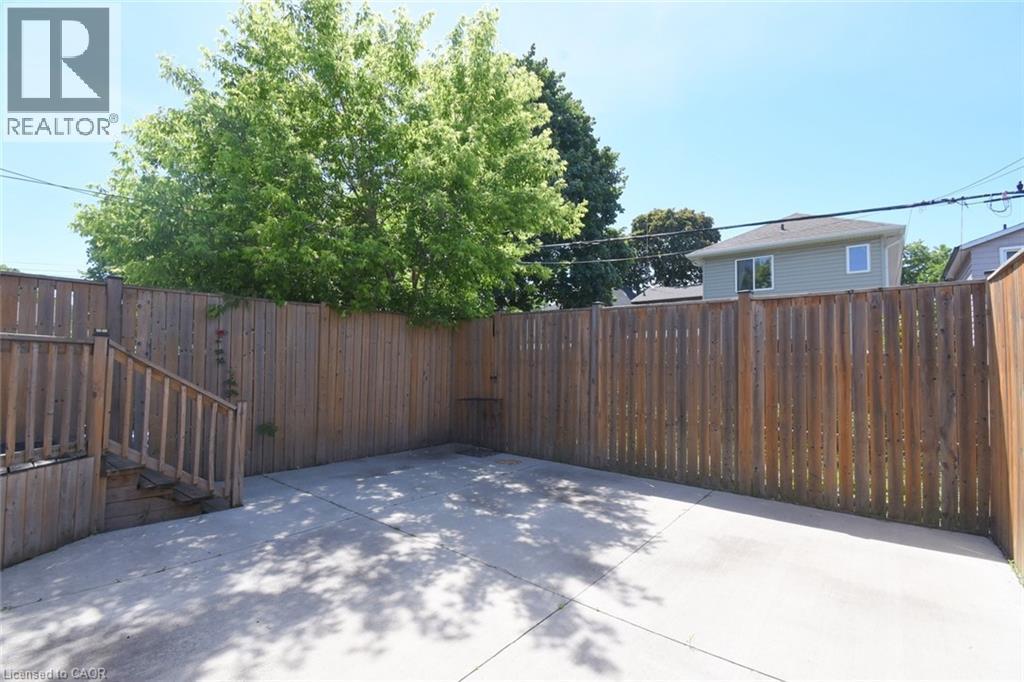 Paved patio area featuring a perimeter privacy fence and a wooden deck with railing - 185 Rosslyn Avenue N, Hamilton, ON - Outdoor