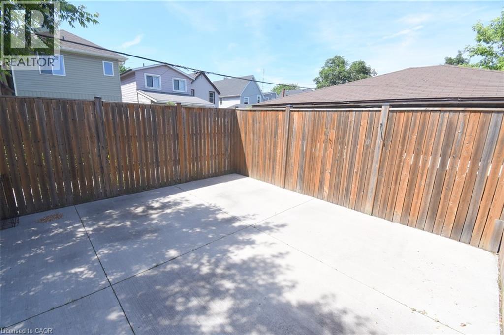 Expansive concrete patio area featuring wood plank fencing - 185 Rosslyn Avenue N, Hamilton, ON - Outdoor