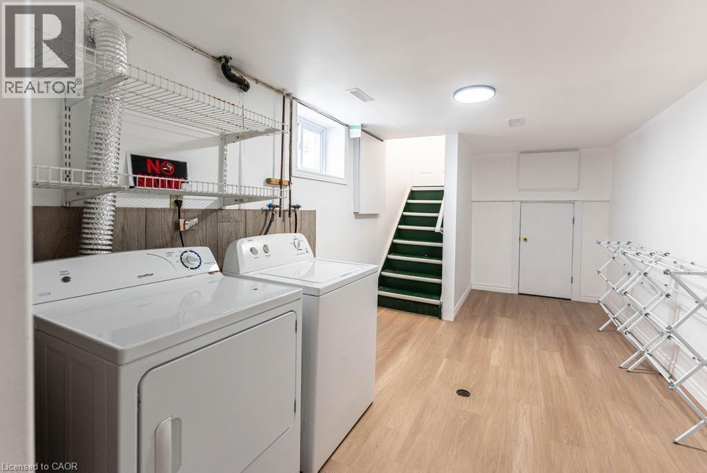 Dedicated laundry area featuring a washer and dryer, wood-finish flooring, and white shelving for organization - 65 Garden Crescent Unit# Lower, Hamilton, ON - Indoor Photo Showing Laundry Room