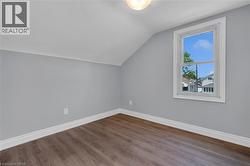 Room featuring wood-finish flooring, light gray walls, white baseboards, and a single window with white trim -