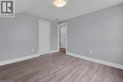 Room featuring light gray walls, wood-finish flooring, white baseboards, and a white bi-fold door -