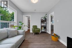 Bright living area featuring wood-finish flooring, light grey walls, white trim, and a large window -