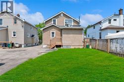 Expansive rear yard featuring a manicured lawn, wood fencing, and a wooden deck with stairs providing outdoor access -