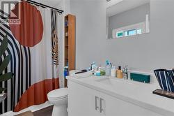 Bathroom featuring a white vanity with an integrated sink, a wall-mounted mirror, and wood-finish flooring -