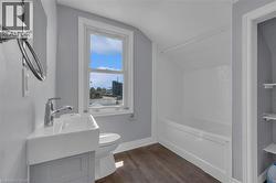 Bathroom featuring a window, white tile shower surround, wood-finish flooring, and a contemporary vanity with an integrated sink -