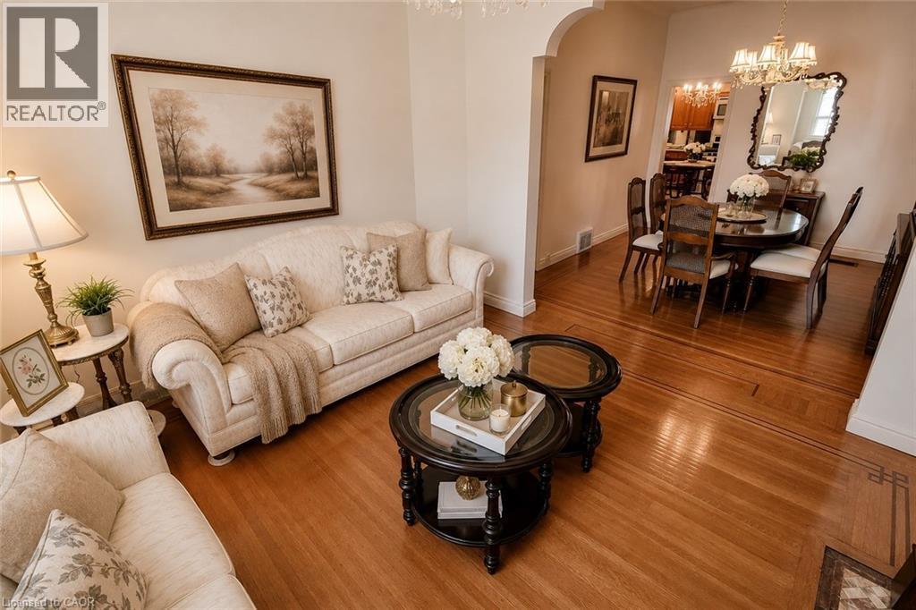 Living area featuring wood-finish flooring with intricate inlay, an arched entryway, and neutral wall tones - 244 Hughson Street N, Hamilton, ON