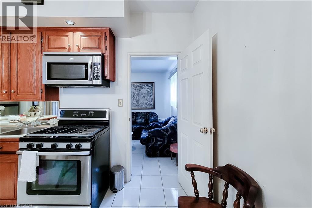 Kitchen featuring wood-finish cabinetry, stainless steel microwave, and stainless steel range - 244 Hughson Street N, Hamilton, ON