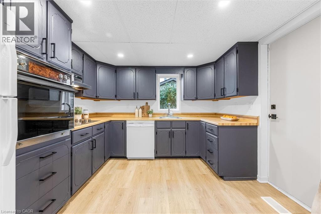 Kitchen featuring dark gray cabinetry, natural wood-finish countertops, and light wood-finish flooring - 11 Ford Street, Hamilton, ON