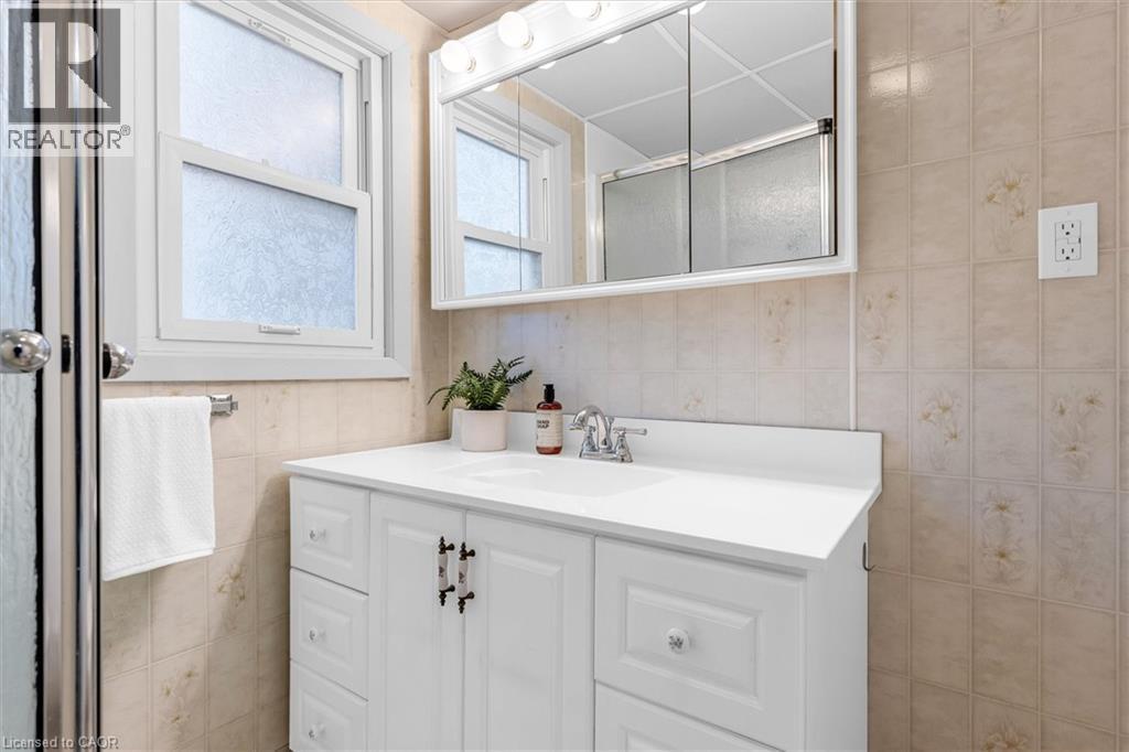 Bathroom featuring a white vanity with integrated sink, chrome faucet, and a wall-mounted mirrored medicine cabinet - 11 Ford Street, Hamilton, ON