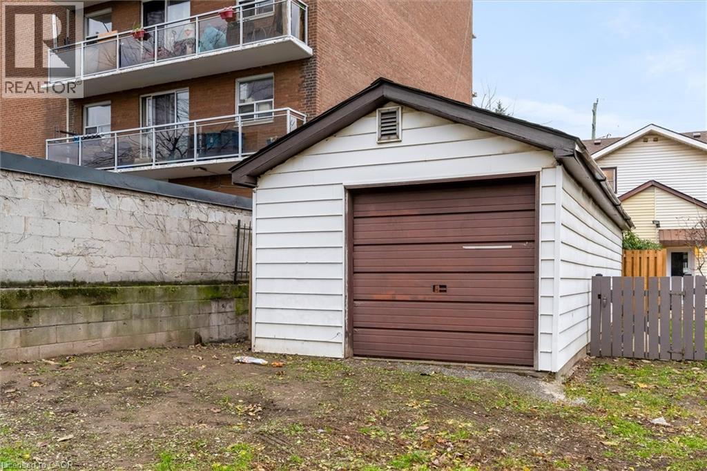 Detached single-car garage featuring a brown sectional door and white siding - 11 Ford Street, Hamilton, ON