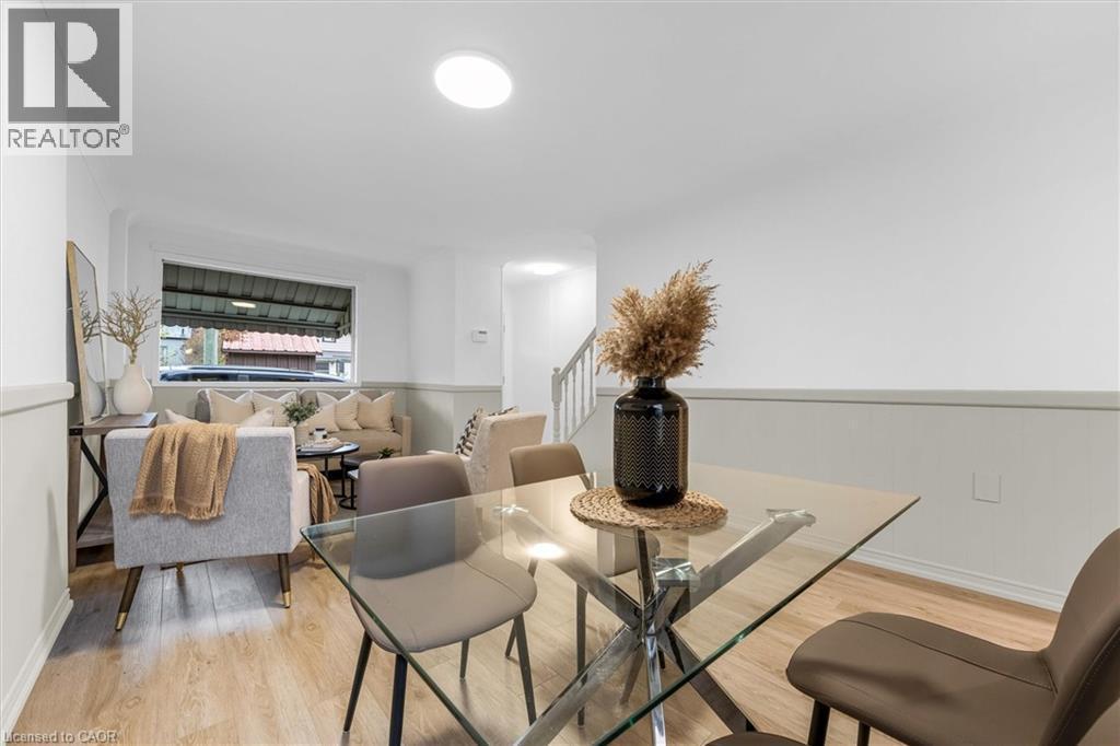 Open-concept living area featuring light wood-finish flooring, white walls with wainscoting, and recessed lighting - 11 Ford Street, Hamilton, ON