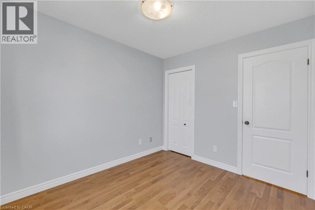 Room featuring wood-finish flooring, light grey painted walls, white trim, and a semi-flush mount ceiling light - 48 Clough Crescent, Guelph, ON