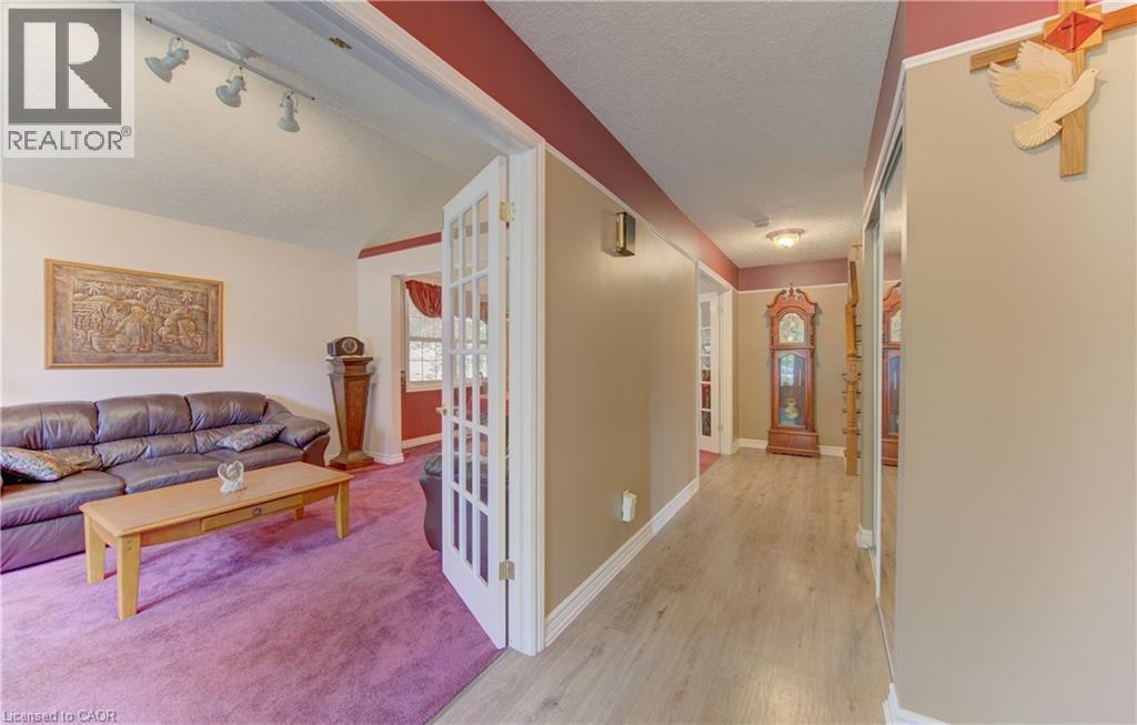 French doors opening to a living area with track lighting, a vaulted ceiling, and plush purple carpeting - 599 Coldstream Drive, Waterloo, ON