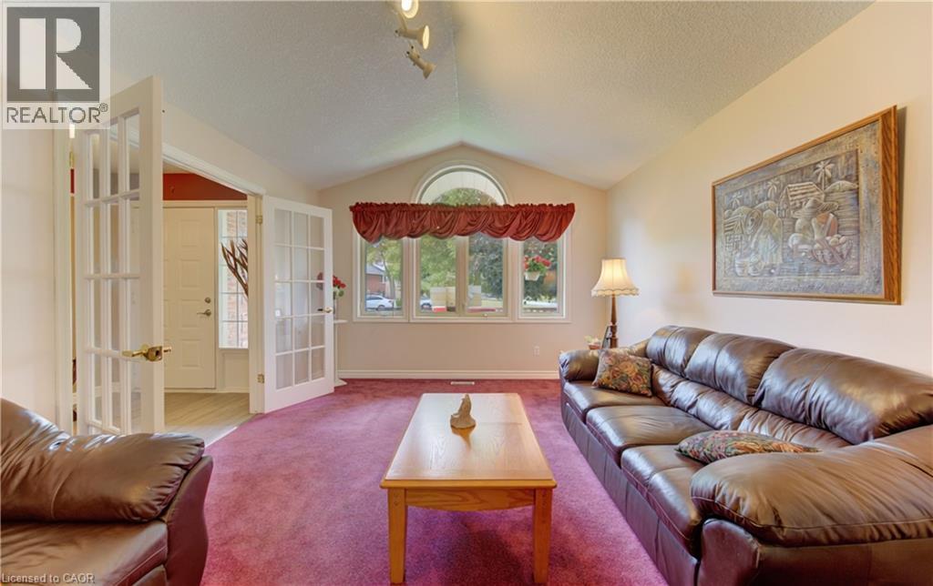 Vaulted ceiling living area featuring a large arched window, multiple window panels, and French doors - 599 Coldstream Drive, Waterloo, ON