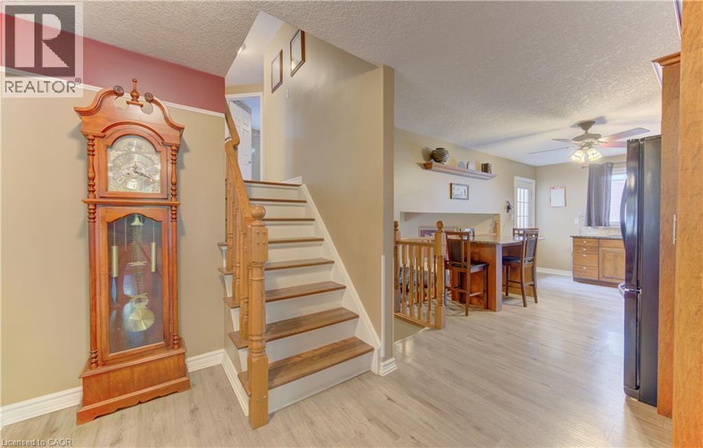Light wood-finish flooring throughout, featuring a hardwood staircase with white risers and a wood banister - 599 Coldstream Drive, Waterloo, ON