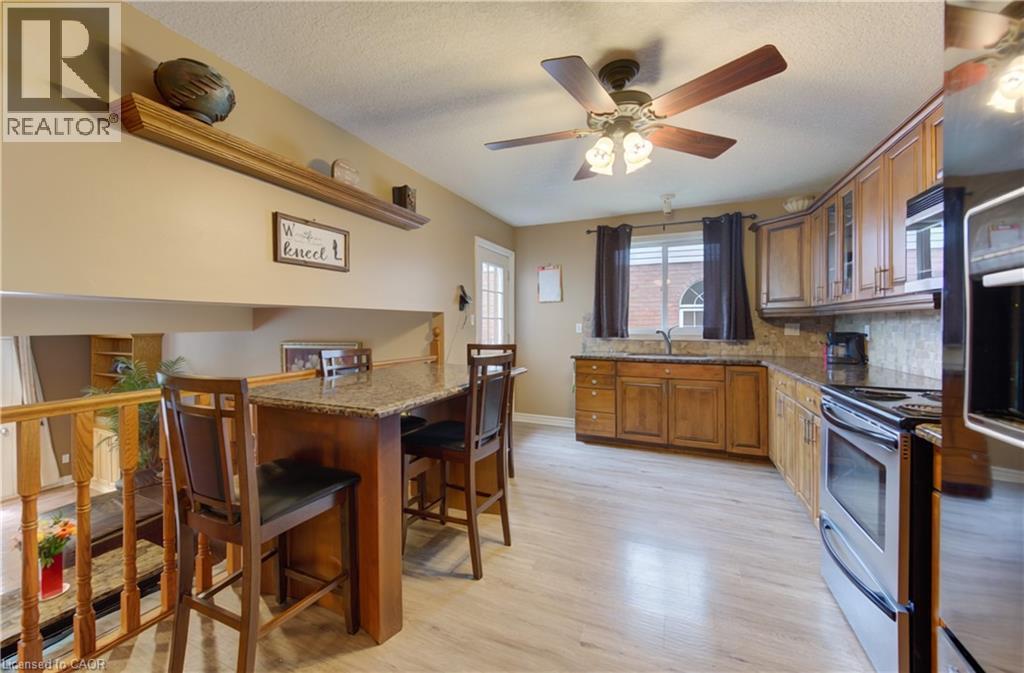 Kitchen featuring light wood-finish flooring, wood cabinetry with upper glass-front accents, and a granite-look countertop - 599 Coldstream Drive, Waterloo, ON
