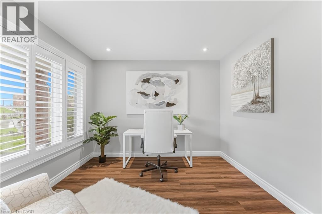 Room featuring three windows with plantation shutters, wood-finish flooring, and recessed ceiling lights - 3332 Testimony Square, Mississauga, ON