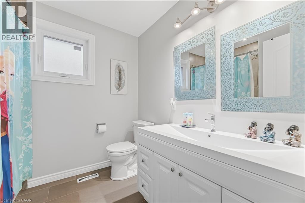 Bathroom featuring a double vanity with integrated sinks, contemporary chrome faucet, and dual framed mirrors - 3332 Testimony Square, Mississauga, ON