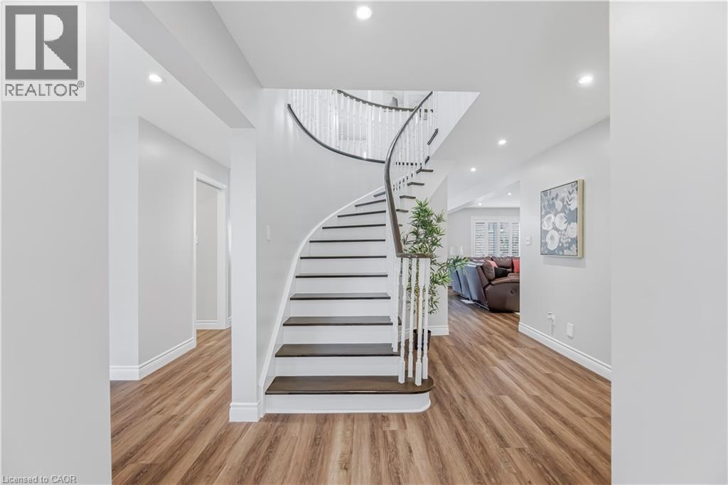 Elegant curved staircase featuring dark wood treads and a white spindle railing - 3332 Testimony Square, Mississauga, ON