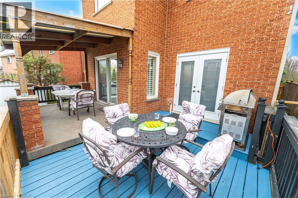 Multi-level outdoor deck featuring a blue-painted lower level, a covered upper level with wooden beams, red brick columns, and a red brick exterior facade - 3332 Testimony Square, Mississauga, ON