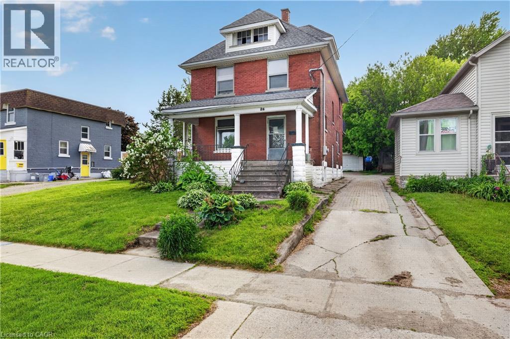 Two-story brick exterior featuring a covered front porch with white columns, a dormer window, and a concrete driveway - 26 Arthur Avenue, St. Thomas, ON - Outdoor With Facade