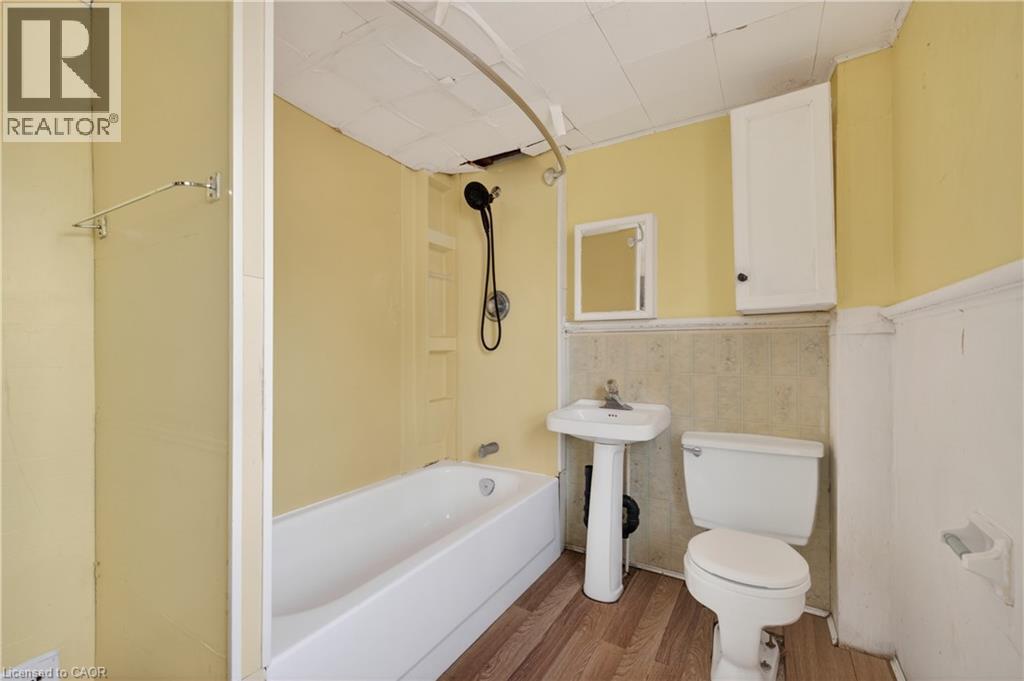 Bathroom featuring a white pedestal sink, toilet, and a bathtub with a shower kit - 26 Arthur Avenue, St. Thomas, ON - Indoor Photo Showing Bathroom