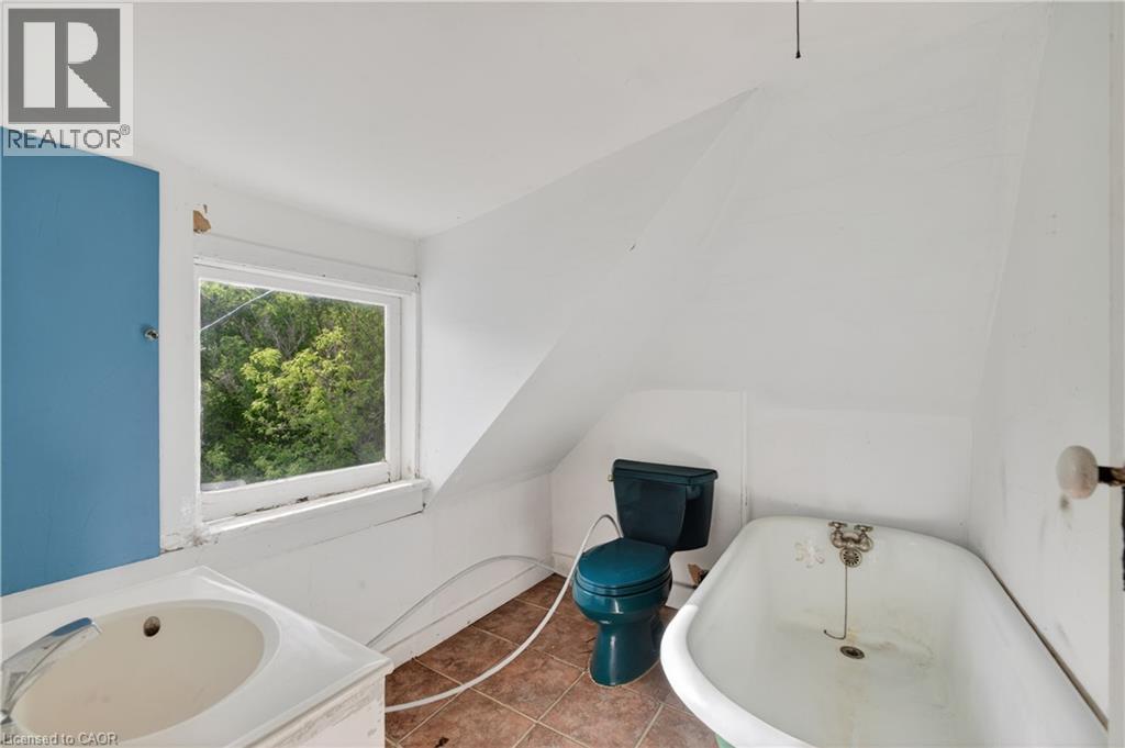 Bathroom featuring a porcelain vanity with a built-in sink, a window overlooking trees, a colored toilet, a classic clawfoot bathtub, and tiled flooring - 26 Arthur Avenue, St. Thomas, ON - Indoor Photo Showing Bathroom