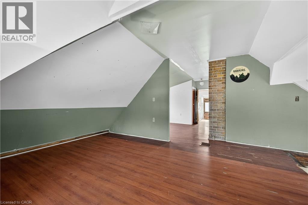 Open room featuring wood-finish flooring, a partial brick column, and sloped ceilings - 26 Arthur Avenue, St. Thomas, ON - Indoor Photo Showing Other Room