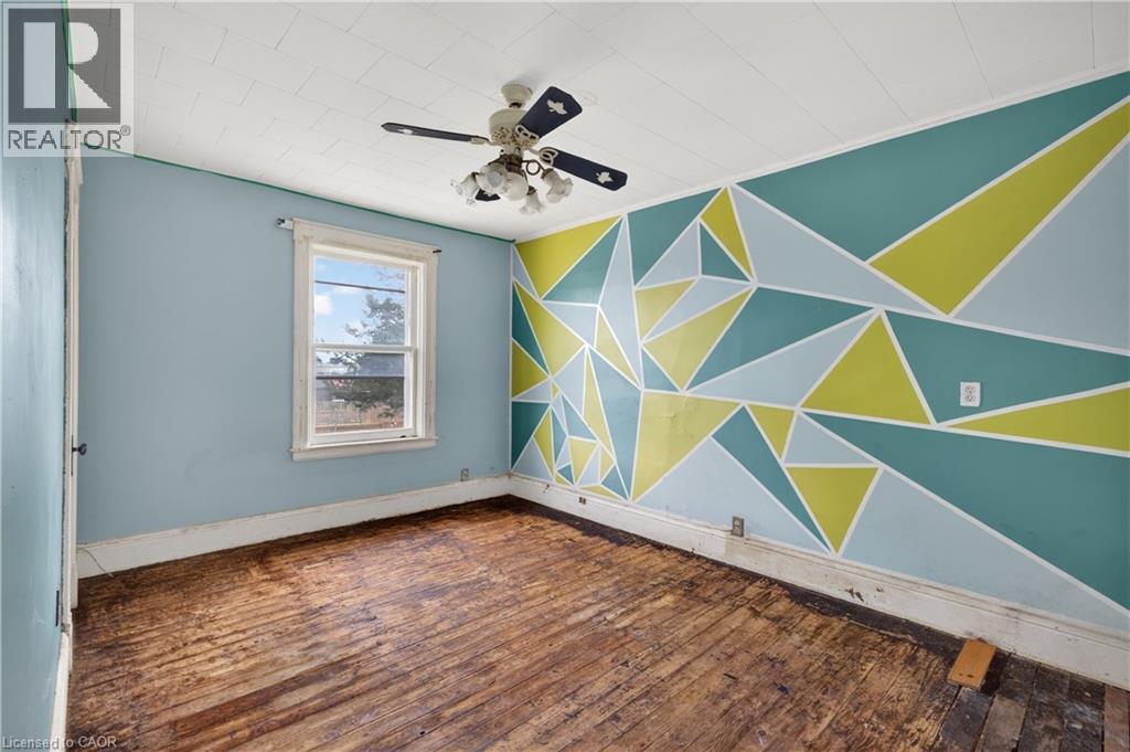 Interior room featuring a geometric accent wall, wood-finish flooring, and a ceiling fan - 26 Arthur Avenue, St. Thomas, ON - Indoor Photo Showing Other Room
