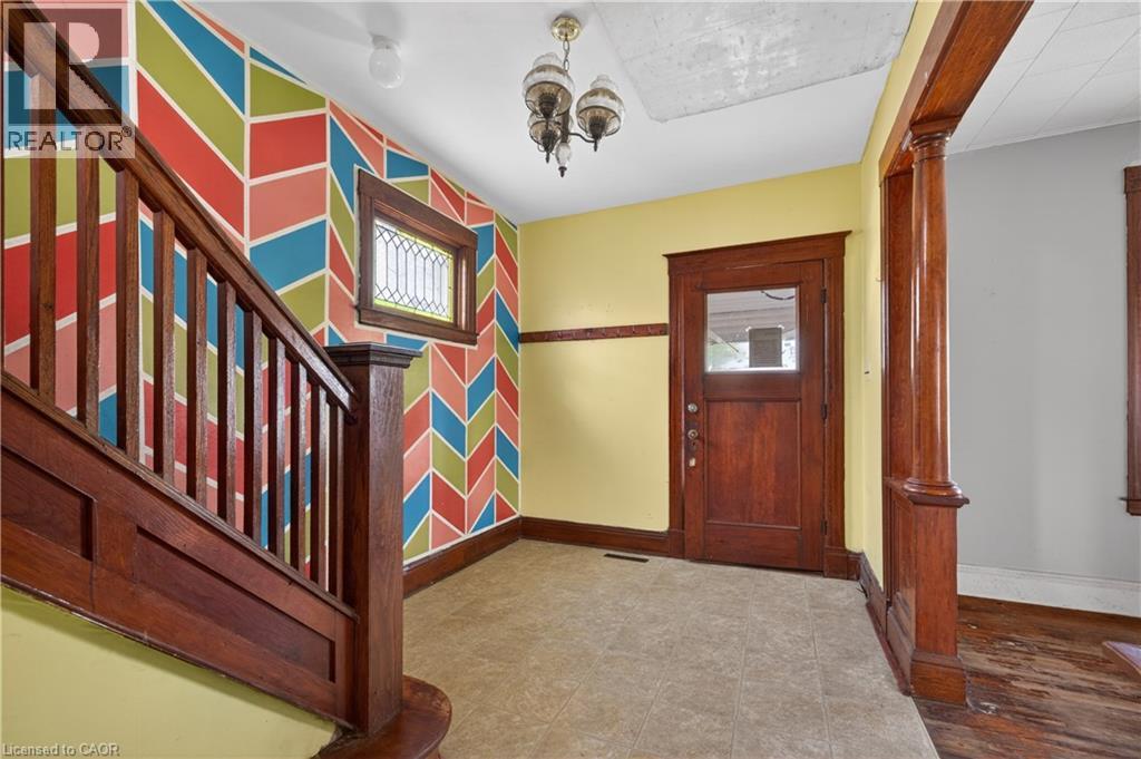 Entryway featuring rich wood-toned staircase and trim, a leaded glass window, and a paneled front door with a glass insert - 26 Arthur Avenue, St. Thomas, ON - Indoor Photo Showing Other Room