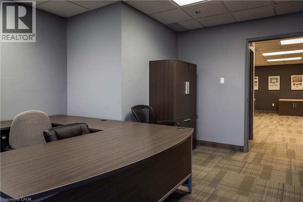 Office space featuring a U-shaped desk with a wood-finish surface, recessed lighting, and patterned carpet flooring - 5100 South Service Road, Burlington, ON