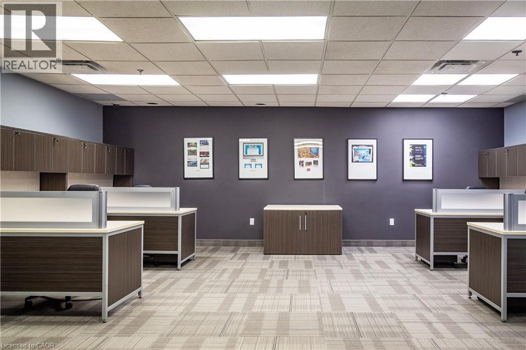 Spacious office interior with modular workstations, built-in overhead cabinetry, and patterned carpet flooring - 5100 South Service Road, Burlington, ON
