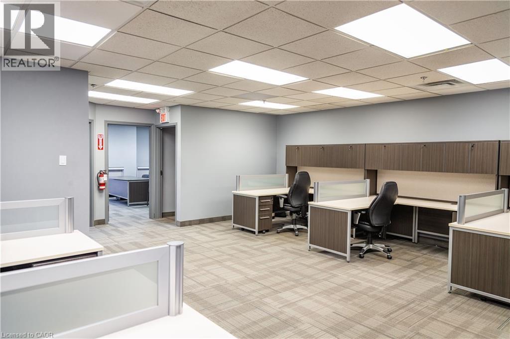 Open office area featuring carpet tile flooring, drop ceiling with integrated lighting, and light gray painted walls - 5100 South Service Road, Burlington, ON