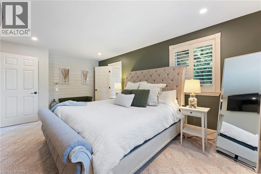 Recessed ceiling lighting illuminates a room featuring a textured accent wall and a window with plantation shutters - 182 Governors Road E, Paris, ON