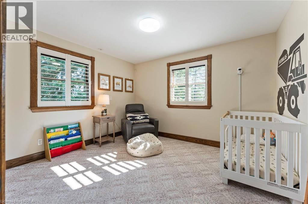 Room featuring neutral wall tones, patterned carpeting, and two windows with white plantation shutters - 182 Governors Road E, Paris, ON