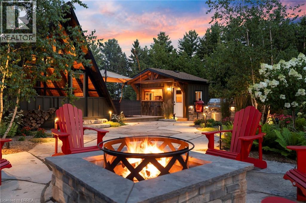 Stone paver patio featuring a built-in fire pit with stone surround, perimeter landscape lighting, an A-frame structure, and a separate detached accessory building - 182 Governors Road E, Paris, ON