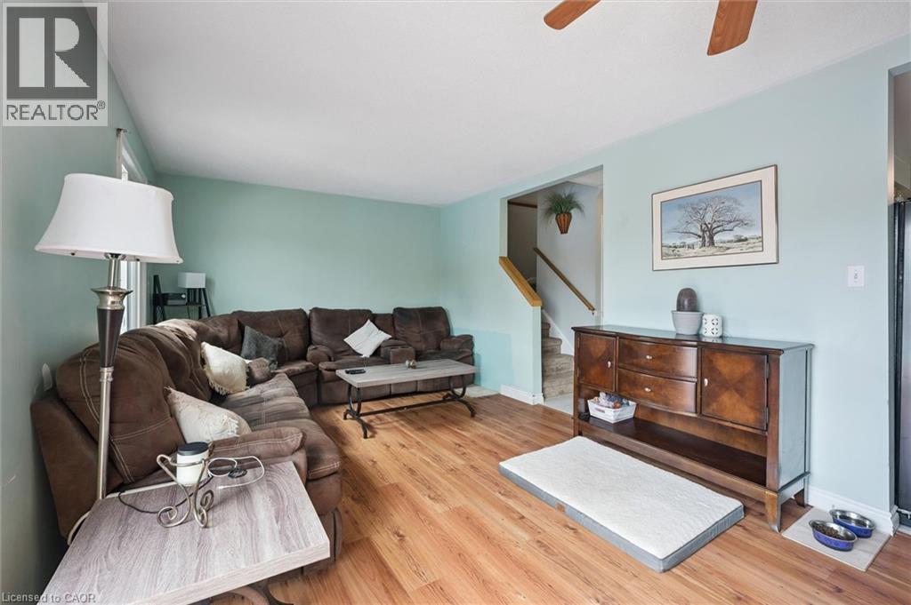 Spacious living area featuring wood-finish flooring, light blue wall paint, and a ceiling fan - 817 Acadia Drive, Hamilton, ON - Indoor Photo Showing Living Room