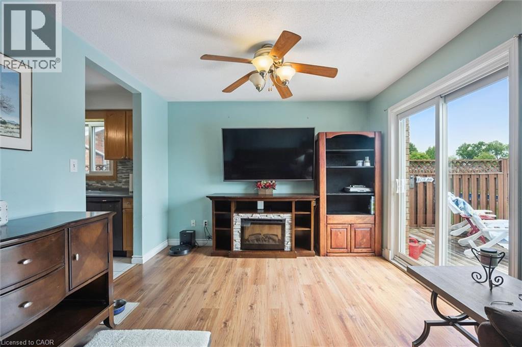 Dining area featuring wood-finish flooring, a built-in electric fireplace, and a ceiling fan - 817 Acadia Drive, Hamilton, ON - Indoor With Fireplace