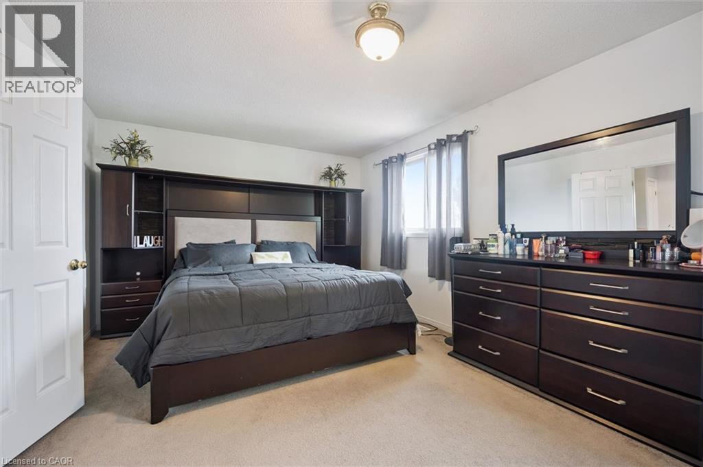 Carpeted bedroom featuring a built-in dark wood headboard unit with integrated shelving and cabinetry - 817 Acadia Drive, Hamilton, ON - Indoor Photo Showing Bedroom