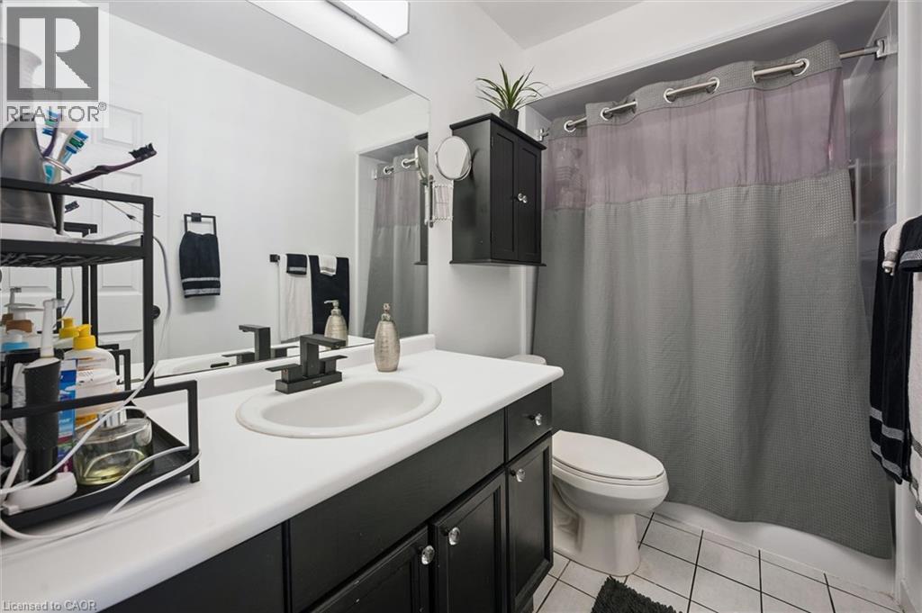 Bathroom featuring a black vanity with a white countertop, an undermount sink, and a matte black faucet - 817 Acadia Drive, Hamilton, ON - Indoor Photo Showing Bathroom