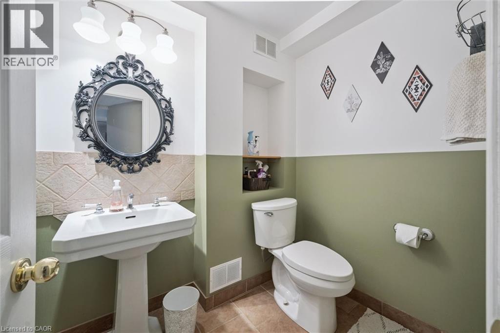 Pedestal sink with chrome fixtures, an ornate dark-framed mirror, and a three-light vanity fixture - 817 Acadia Drive, Hamilton, ON - Indoor Photo Showing Bathroom