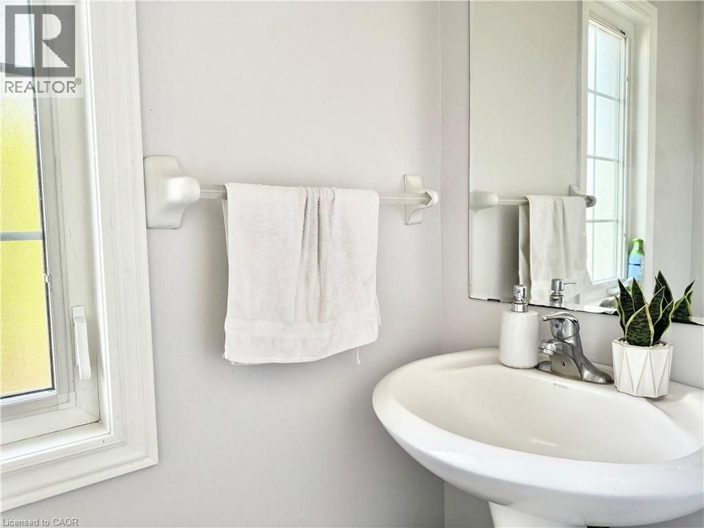 Pedestal sink with chrome faucet, complemented by a large wall-mounted mirror - 1333 Countrystone Drive, Kitchener, ON
