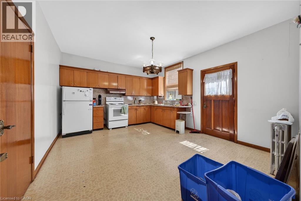 Expansive kitchen featuring wood cabinetry, a built-in oven, refrigerator, and a matching wood door - 16 Mulberry Street, Hamilton, ON