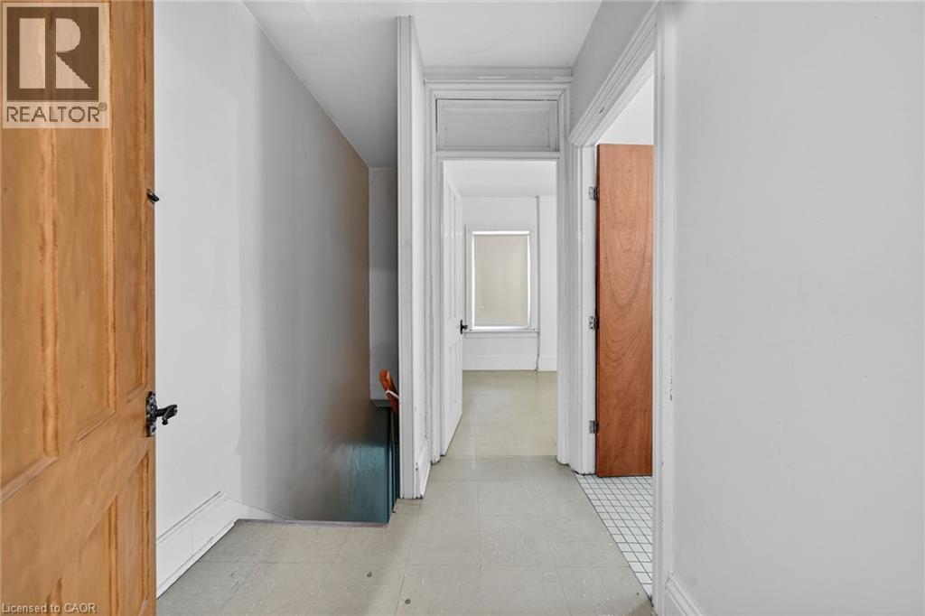 Hallway with light-toned flooring, white walls, and wood panel doors - 16 Mulberry Street, Hamilton, ON